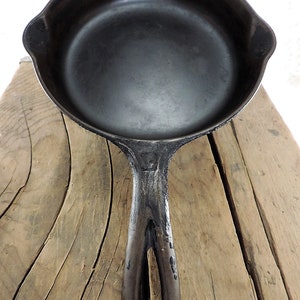 May include: A black cast iron skillet with a loop handle. The skillet is empty and has a smooth, dark surface.