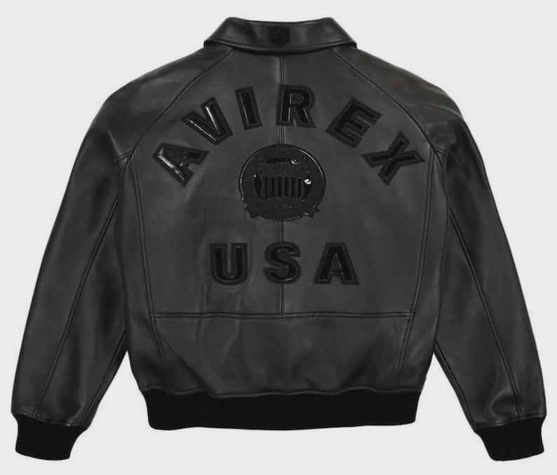 May include: Black leather jacket with the word "AVIREX" arched across the shoulders and "USA" below a circular emblem. The jacket has a ribbed hem and cuffs. The back of the jacket is the focus of the image.