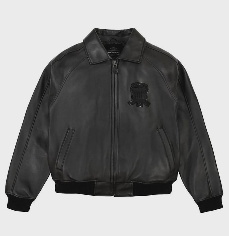 May include: Black leather bomber jacket with a collar, zipper closure, and a patch on the chest. The jacket has a ribbed hem and cuffs. The brand name is visible on the collar.