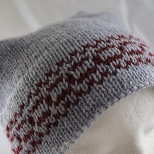 May include: A gray knitted hat with a red and gray striped pattern.