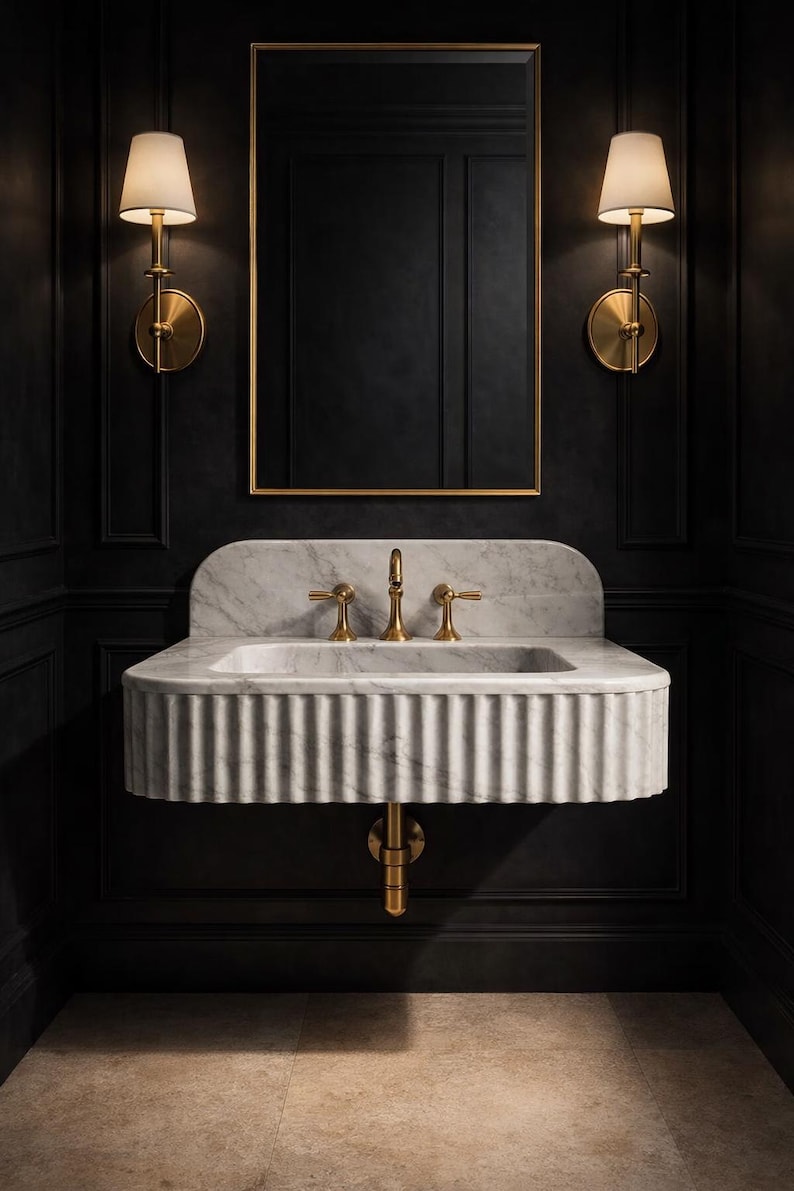 May include: A luxurious bathroom interior featuring a marble sink with gold fixtures, set against a black paneled wall. Two sconces with cream-colored shades flank a gold-framed mirror. The sink has a ribbed design.