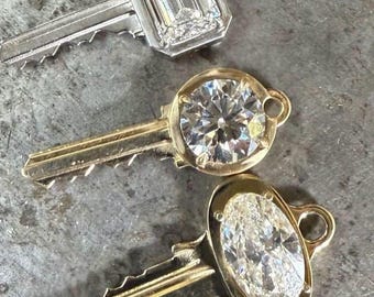May include: Three decorative keys with diamond-shaped embellishments. The top key has a rectangular diamond, while the middle key features a round diamond. The bottom key showcases an oval diamond. All keys have a metallic finish.