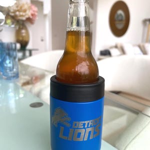 Show your football pride and keep your favorite drink ice cold with this Detroit Lions-inspired 12 oz insulated bottle cooler. Featuring a laser-engraved design on a durable, powder-coated blue finish, it combines style, function, and team spirit in one premium game day accessory. The double-wall stainless steel insulation keeps drinks at the perfect temperature longer, making it ideal for tailgates, backyard barbecues, camping trips, man caves, or just relaxing while watching the big game.