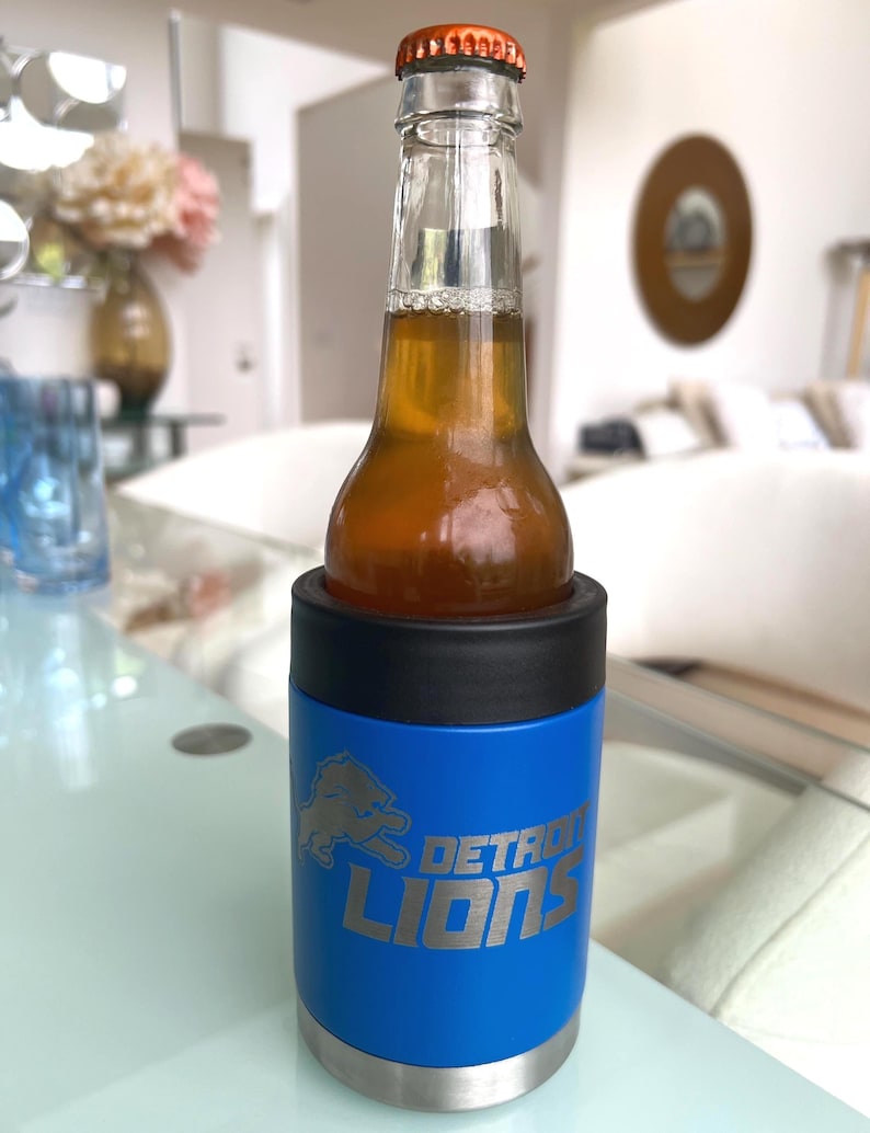 Show your football pride and keep your favorite drink ice cold with this Detroit Lions-inspired 12 oz insulated bottle cooler. Featuring a laser-engraved design on a durable, powder-coated blue finish, it combines style, function, and team spirit in one premium game day accessory. The double-wall stainless steel insulation keeps drinks at the perfect temperature longer, making it ideal for tailgates, backyard barbecues, camping trips, man caves, or just relaxing while watching the big game.