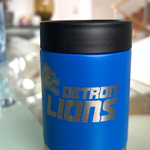 Show your football pride and keep your favorite drink ice cold with this Detroit Lions-inspired 12 oz insulated bottle cooler. Featuring a laser-engraved design on a durable, powder-coated blue finish, it combines style, function, and team spirit in one premium game day accessory. The double-wall stainless steel insulation keeps drinks at the perfect temperature longer, making it ideal for tailgates, backyard barbecues, camping trips, man caves, or just relaxing while watching the big game.