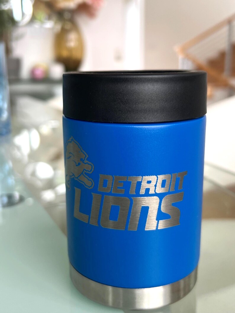 Show your football pride and keep your favorite drink ice cold with this Detroit Lions-inspired 12 oz insulated bottle cooler. Featuring a laser-engraved design on a durable, powder-coated blue finish, it combines style, function, and team spirit in one premium game day accessory. The double-wall stainless steel insulation keeps drinks at the perfect temperature longer, making it ideal for tailgates, backyard barbecues, camping trips, man caves, or just relaxing while watching the big game.