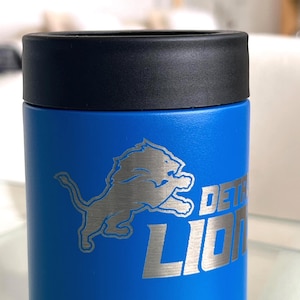 Show your football pride and keep your favorite drink ice cold with this Detroit Lions-inspired 12 oz insulated bottle cooler. Featuring a laser-engraved design on a durable, powder-coated blue finish, it combines style, function, and team spirit in one premium game day accessory. The double-wall stainless steel insulation keeps drinks at the perfect temperature longer, making it ideal for tailgates, backyard barbecues, camping trips, man caves, or just relaxing while watching the big game.