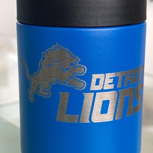 Show your football pride and keep your favorite drink ice cold with this Detroit Lions-inspired 12 oz insulated bottle cooler. Featuring a laser-engraved design on a durable, powder-coated blue finish, it combines style, function, and team spirit in one premium game day accessory. The double-wall stainless steel insulation keeps drinks at the perfect temperature longer, making it ideal for tailgates, backyard barbecues, camping trips, man caves, or just relaxing while watching the big game.
