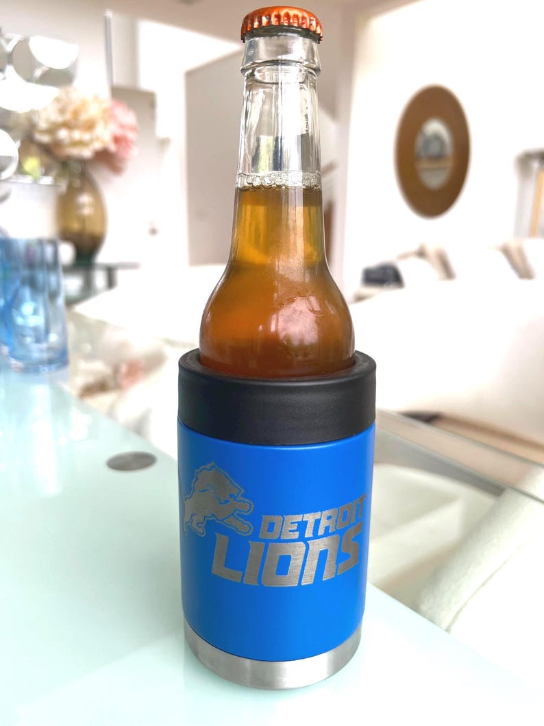 Show your football pride and keep your favorite drink ice cold with this Detroit Lions-inspired 12 oz insulated bottle cooler. Featuring a laser-engraved design on a durable, powder-coated blue finish, it combines style, function, and team spirit in one premium game day accessory. The double-wall stainless steel insulation keeps drinks at the perfect temperature longer, making it ideal for tailgates, backyard barbecues, camping trips, man caves, or just relaxing while watching the big game.