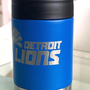 Show your football pride and keep your favorite drink ice cold with this Detroit Lions-inspired 12 oz insulated bottle cooler. Featuring a laser-engraved design on a durable, powder-coated blue finish, it combines style, function, and team spirit in one premium game day accessory. The double-wall stainless steel insulation keeps drinks at the perfect temperature longer, making it ideal for tailgates, backyard barbecues, camping trips, man caves, or just relaxing while watching the big game.