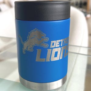 Show your football pride and keep your favorite drink ice cold with this Detroit Lions-inspired 12 oz insulated bottle cooler. Featuring a laser-engraved design on a durable, powder-coated blue finish, it combines style, function, and team spirit in one premium game day accessory. The double-wall stainless steel insulation keeps drinks at the perfect temperature longer, making it ideal for tailgates, backyard barbecues, camping trips, man caves, or just relaxing while watching the big game.