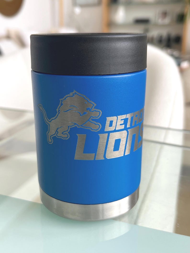 Show your football pride and keep your favorite drink ice cold with this Detroit Lions-inspired 12 oz insulated bottle cooler. Featuring a laser-engraved design on a durable, powder-coated blue finish, it combines style, function, and team spirit in one premium game day accessory. The double-wall stainless steel insulation keeps drinks at the perfect temperature longer, making it ideal for tailgates, backyard barbecues, camping trips, man caves, or just relaxing while watching the big game.