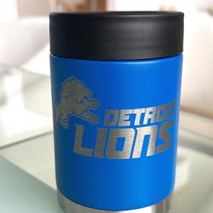 Show your football pride and keep your favorite drink ice cold with this Detroit Lions-inspired 12 oz insulated bottle cooler. Featuring a laser-engraved design on a durable, powder-coated blue finish, it combines style, function, and team spirit in one premium game day accessory. The double-wall stainless steel insulation keeps drinks at the perfect temperature longer, making it ideal for tailgates, backyard barbecues, camping trips, man caves, or just relaxing while watching the big game.