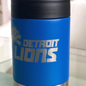 Show your football pride and keep your favorite drink ice cold with this Detroit Lions-inspired 12 oz insulated bottle cooler. Featuring a laser-engraved design on a durable, powder-coated blue finish, it combines style, function, and team spirit in one premium game day accessory. The double-wall stainless steel insulation keeps drinks at the perfect temperature longer, making it ideal for tailgates, backyard barbecues, camping trips, man caves, or just relaxing while watching the big game.