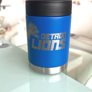 Show your football pride and keep your favorite drink ice cold with this Detroit Lions-inspired 12 oz insulated bottle cooler. Featuring a laser-engraved design on a durable, powder-coated blue finish, it combines style, function, and team spirit in one premium game day accessory. The double-wall stainless steel insulation keeps drinks at the perfect temperature longer, making it ideal for tailgates, backyard barbecues, camping trips, man caves, or just relaxing while watching the big game.