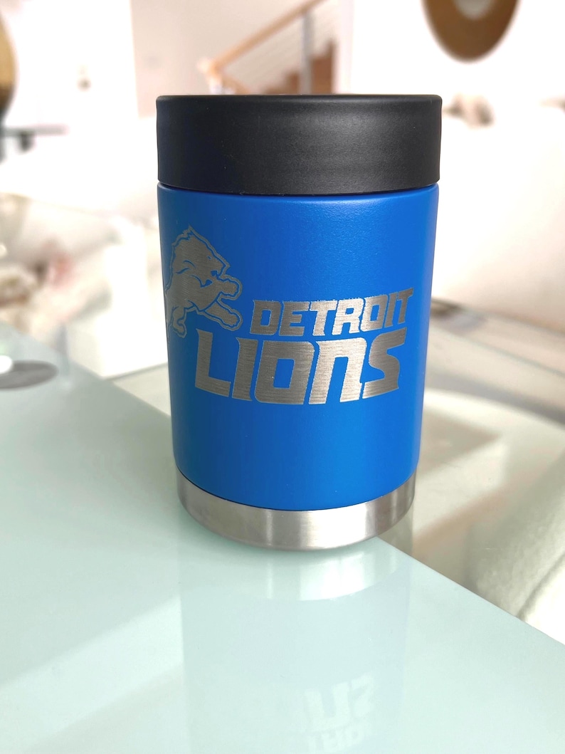 Show your football pride and keep your favorite drink ice cold with this Detroit Lions-inspired 12 oz insulated bottle cooler. Featuring a laser-engraved design on a durable, powder-coated blue finish, it combines style, function, and team spirit in one premium game day accessory. The double-wall stainless steel insulation keeps drinks at the perfect temperature longer, making it ideal for tailgates, backyard barbecues, camping trips, man caves, or just relaxing while watching the big game.