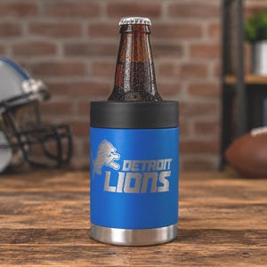 Show your football pride and keep your favorite drink ice cold with this Detroit Lions-inspired 12 oz insulated bottle cooler. Featuring a laser-engraved design on a durable, powder-coated blue finish, it combines style, function, and team spirit in one premium game day accessory. The double-wall stainless steel insulation keeps drinks at the perfect temperature longer, making it ideal for tailgates, backyard barbecues, camping trips, man caves, or just relaxing while watching the big game.