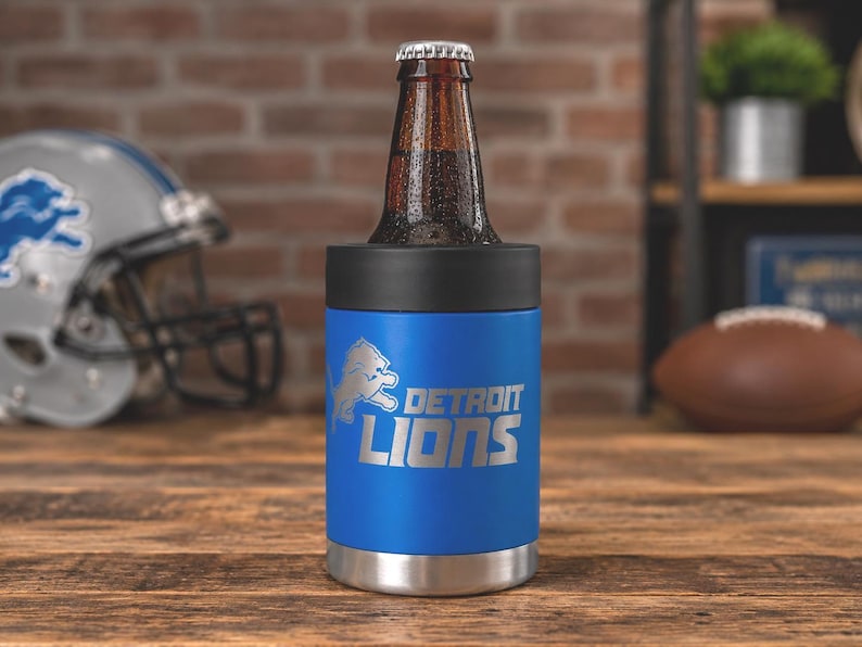 Show your football pride and keep your favorite drink ice cold with this Detroit Lions-inspired 12 oz insulated bottle cooler. Featuring a laser-engraved design on a durable, powder-coated blue finish, it combines style, function, and team spirit in one premium game day accessory. The double-wall stainless steel insulation keeps drinks at the perfect temperature longer, making it ideal for tailgates, backyard barbecues, camping trips, man caves, or just relaxing while watching the big game.