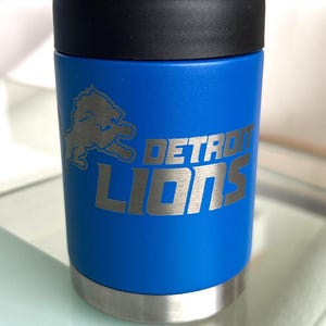 Show your football pride and keep your favorite drink ice cold with this Detroit Lions-inspired 12 oz insulated bottle cooler. Featuring a laser-engraved design on a durable, powder-coated blue finish, it combines style, function, and team spirit in one premium game day accessory. The double-wall stainless steel insulation keeps drinks at the perfect temperature longer, making it ideal for tailgates, backyard barbecues, camping trips, man caves, or just relaxing while watching the big game.