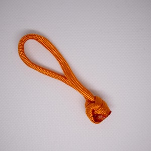 Op de afbeelding: Een oranje koordlus met een geknoopt uiteinde. Het koord heeft een levendige oranje kleur en de knoop is strak geweven. De lus is ontworpen voor gemakkelijk vastpakken en ophangen. Het item staat tegen een effen witte achtergrond.