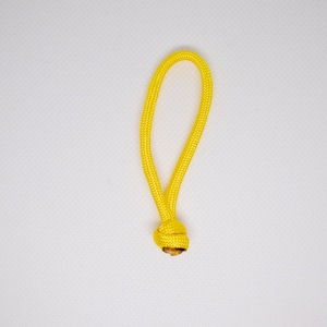 Könnte beinhalten: Eine leuchtend gelbe Kordelschlaufe mit einem Knoten an der Basis. Die Kordel besteht aus einem gewebten Material und ist vor einem weißen Hintergrund platziert. Die Schlaufe ist etwa 10 cm lang.