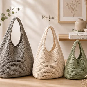 Può includere: Tre borse hobo all'uncinetto di diverse dimensioni e colori. La borsa grande è grigia, quella media è color crema e la piccola è verde salvia. Ogni borsa presenta un manico integrato unico e un motivo a maglia intrecciata e testurizzata.