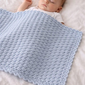 K&ouml;nnte beinhalten: Eine hellblaue Babydecke mit einem strukturierten, sich wiederholenden Stichmuster und einem gewellten Rand. Die Decke ist rechteckig geformt und weist eine durchgehend konsistente und dichte H&auml;kelkonstruktion auf der gesamten Oberfl&auml;che auf.