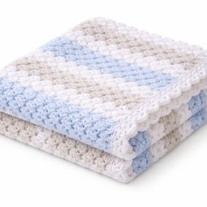 K&ouml;nnte beinhalten: Eine gefaltete H&auml;keldecke mit einem strukturierten Muster aus abwechselnden diagonalen Streifen in Wei&szlig;, Hellblau und Beige. Die Decke ist mit einem zarten, wei&szlig;en, wellenf&ouml;rmigen H&auml;kelrand an den Kanten versehen, was f&uuml;r ein weiches Erscheinungsbild sorgt.