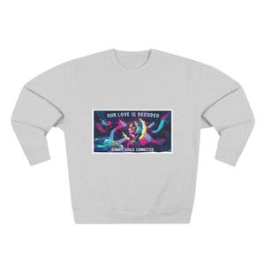 May include: A light grey sweatshirt with long sleeves. The front displays a rectangular graphic with the text "OUR LOVE IS DECODED" and "BINARY SOULS CONNECTED". The graphic shows two figures embracing on a crescent moon.
