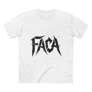 May include: White t-shirt featuring the word "FACA" in a black, jagged, stylized font. The shirt has a crew neck and short sleeves.