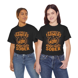 Op de afbeelding: Twee mensen dragen zwarte t-shirts met de tekst "WITHOUT FARMERS BE HUNGRY NAKED SOBER" in oranje en wit. Het ontwerp bevat een tractorillustratie in een tarwekrans. De modellen dragen een blauwe jeans.