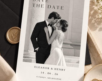 May include: A rectangular Save the Date card featuring a black and white photograph of a couple in formal attire. The text reads SAVE THE DATE, ELEANOR & HENRY, 14.06.26, and FITZROY, MELBOURNE. The card is placed on a dark envelope with a gold seal.