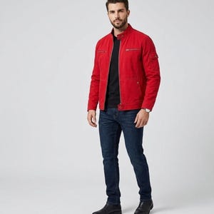 May include: A bright red jacket with a stand-up collar, silver-tone zip, and multiple pockets, worn over a plain black t-shirt with dark blue denim jeans and black leather shoes. The jacket features a small pocket on the left sleeve.
