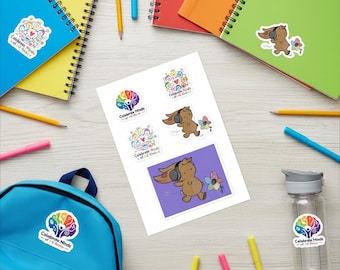 Puede incluir: Una hoja de pegatinas con ilustraciones de un conejo marrón con auriculares, un icono de árbol con forma de cerebro colorido y el texto Celebrate Minds of All Kinds. La hoja está rodeada de cuadernos de espiral, una mochila azul, una botella y lápices.