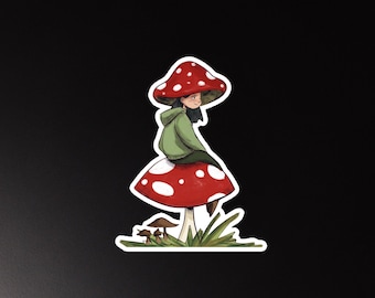 Puede incluir: Una ilustración adhesiva que muestra a una persona de cabello oscuro con una sudadera verde, sentada sobre una seta roja grande con puntos blancos. La persona está bajo un sombrero de seta rojo a juego. Pequeñas setas marrones y hierba abajo.