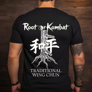 Op de afbeelding: Zwart t-shirt met een witte afbeelding op de rug. De afbeelding bevat de tekst "Root of Kombat", een boomillustratie, Chinese karakters en "Traditional Wing Chun".