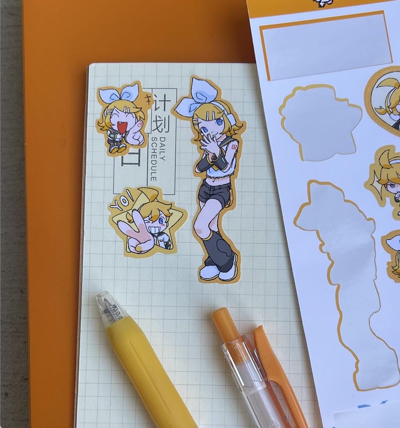 May include: A collection of stickers featuring anime-style characters with blue bows and yellow hair. The stickers are on a notebook with the words "DAILY SCHEDULE" and a yellow pen. The stickers are in various poses.