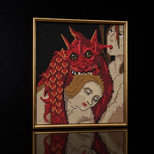 Pode incluir: Uma pintura de diamante emoldurada apresentando um drag&atilde;o vermelho com escamas texturizadas e olhos grandes atr&aacute;s de uma pessoa de pele clara e cabelo loiro. A obra est&aacute; sobre um fundo preto em uma moldura fina de cor dourada.