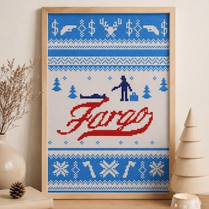 May include: A framed cross-stitch embroidery featuring a blue and white Nordic-style pattern with the red text Fargo in the center. The design includes pixelated motifs of a person, a vehicle, trees, and geometric shapes in a repeating horizontal layout.