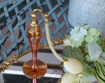Frasco atomizador de perfume antiguo de cristal Art Déco color ámbar, firmado por DeVilbiss, con tapa dorada ornamentada.