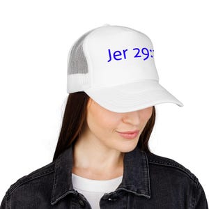 May include: White trucker hat with a mesh back and a curved brim. The hat features the blue text "Jer 29:". The hat is worn by a person wearing a black denim jacket.
