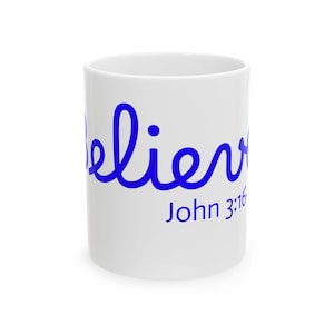 May include: White ceramic mug featuring the word "Believe" in blue script. The text "John 3:16" is printed below in blue. The mug is cylindrical and has a glossy finish.