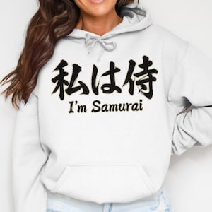 May include: White hooded sweatshirt with a front pocket and a drawstring. The front displays black Japanese characters above the English phrase "I'm Samurai". The text is centrally placed.