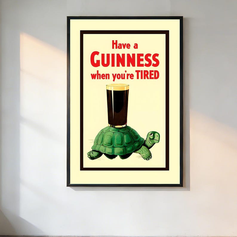 May include: Framed vintage poster with a black border. The poster features a green turtle with a pint of Guinness balanced on its back. The text reads "Have a GUINNESS when you're TIRED" in red and white.