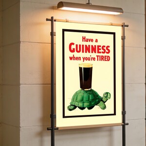 May include: A vintage-style Guinness advertisement poster. The poster features a green turtle with a pint of Guinness balanced on its back. The text reads "Have a Guinness when you're TIRED" in red letters.