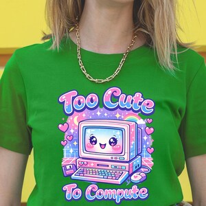 May include: Green t-shirt featuring a retro computer graphic with a smiling face, hearts, and a rainbow. The text "Too Cute To Compute" is displayed in a playful font.