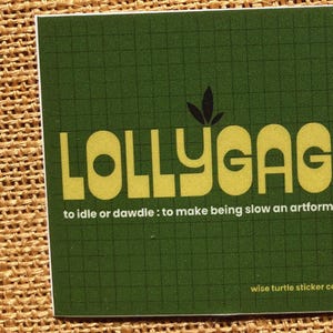 May include: A square sticker with a dark green grid background. The text LOLLYGAG is printed in large yellow letters with a small leaf icon above. Below, the text reads: to idle or dawdle : to make being slow an artform. Wise turtle sticker co is at the bottom.