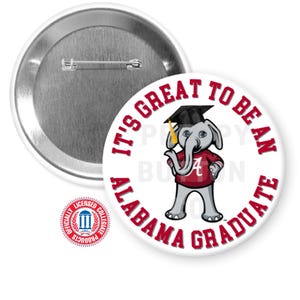 Könnte beinhalten: Ein weißer Button mit Anstecknadel, der einen Cartoon-Elefanten mit Abschlusskappe und einem weinroten Hemd mit dem Buchstaben "A" zeigt. Der Button trägt den Text "IT'S GREAT TO BE AN ALABAMA GRADUATE" in weinroter Schrift.