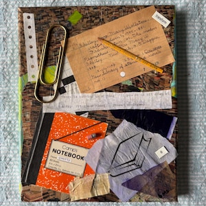 May include: Mixed media artwork featuring a collage of vintage ephemera. Includes a library card, a yellow pencil, a gold paper clip, and an orange notebook. The notebook measures 4 in x 3.75 in. The artwork has text from Ernest Hemingway.