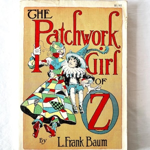 May include: The cover of a vintage children's book titled "The Patchwork Girl of Oz" by L. Frank Baum. The cover features a colorful illustration of a patchwork doll and a girl in a blue hat sitting on a large red letter Z.